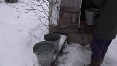 İnsanlar temiz suyu, kışın yağan kara yakın bir kovaya döker.