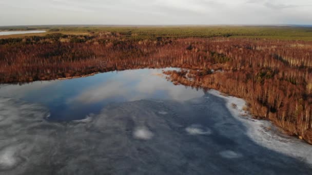 Заморожене озеро з тонким льодом і водою з дзеркалом неба на весняному заході сонця — стокове відео