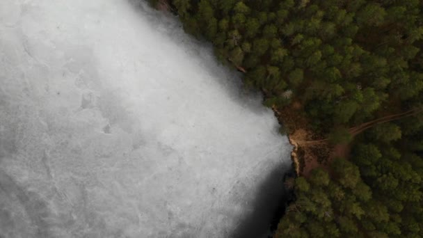 발자국이 달린 얇은 얼음이 얼어붙은 호수의 도로와 숲 해변 — 비디오