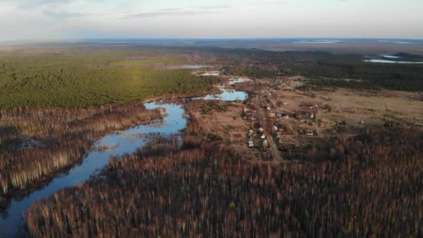 Dorp in het bos bij grote brede rivier met houten brug in het najaar voorjaar — Stockvideo