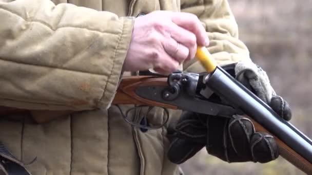 Człowiek noszący Telogreikę ładuje amunicję do strzelby z dźwiękiem. — Wideo stockowe