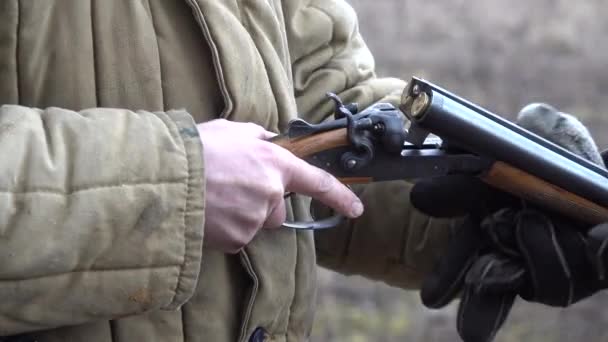 Mann mit Waffe zieht Granatmunition aus Schrotflinte mit Geräuschen und Rauch