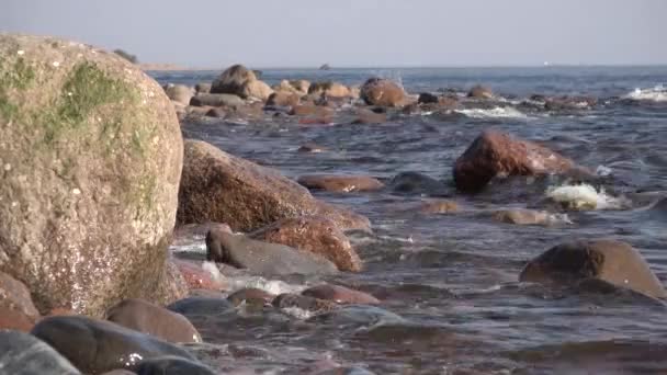 Piccole onde rotolano sulla spiaggia rocciosa. Grande lago o mare con pietre . — Video Stock