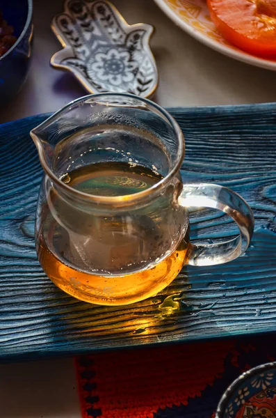 Güneş ışınları yeşil çay dolu bir cam kaseden geçer. Çay tepsisinde çay dolu bir kase var.