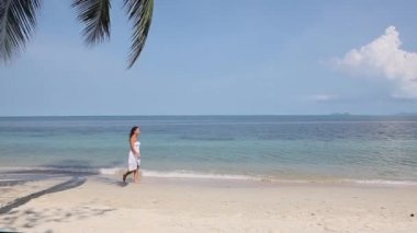 Beyaz elbiseli bir kız sahilde yürüyor