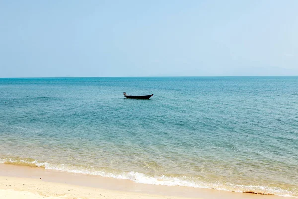 A boat in the sea without people near a deserted beach