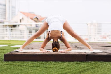 Güzel kadın bir çatı katı terasında açık havada yoga yaparken