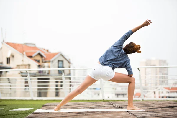 Mooie vrouw doet yoga buiten op een dakterras — Stockfoto