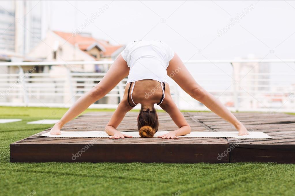 Beautiful woman doing yoga outdoors on a rooftop terrace