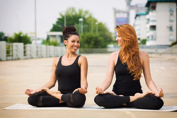 Dos hermosas mujeres haciendo yoga al aire libre en un barrio urbano — Foto de Stock