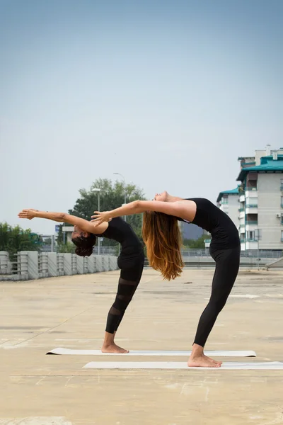 Dos hermosas mujeres haciendo yoga al aire libre en un barrio urbano — Foto de Stock