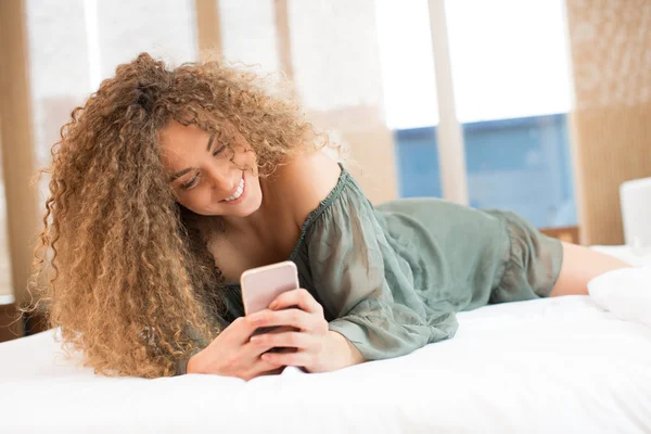 Hermosa chica mensajes de texto en la cama —  Fotos de Stock