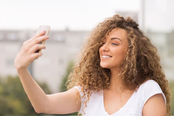 Gyönyörű göndör haj lány vesz selfie — Stock Fotó