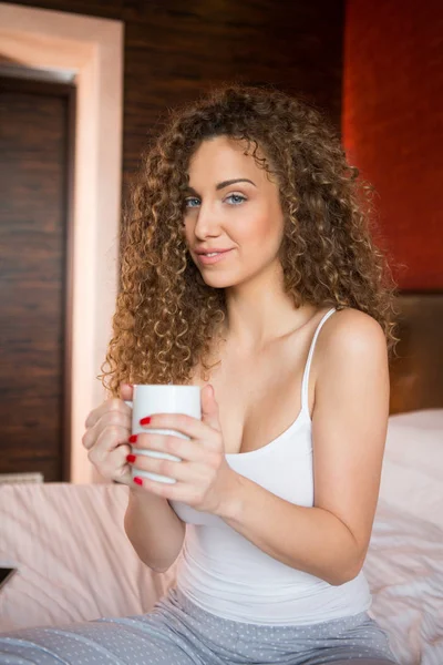 Belle fille au lit avec une tasse de thé chaud — Photo