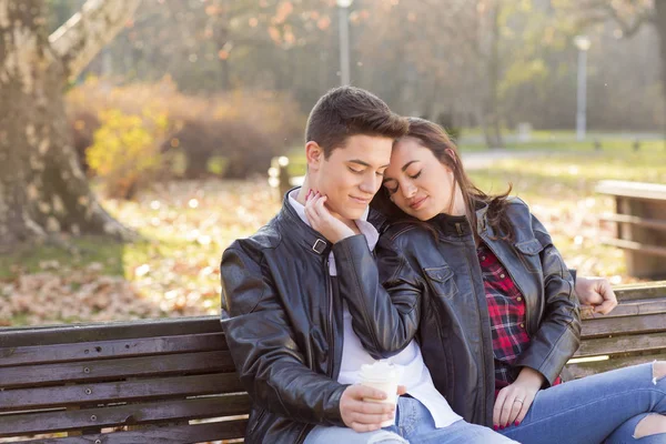 Feliz joven pareja sentada en un banco en el parque — Foto de Stock