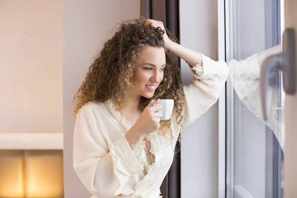 Женщина с чашкой кофе у окна — стоковое фото