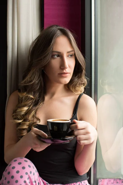 Jeune femme avec une tasse de café assis près de la fenêtre — Photo