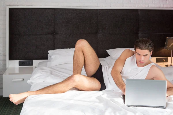 Handsome man in bed with laptop — Stock Photo, Image