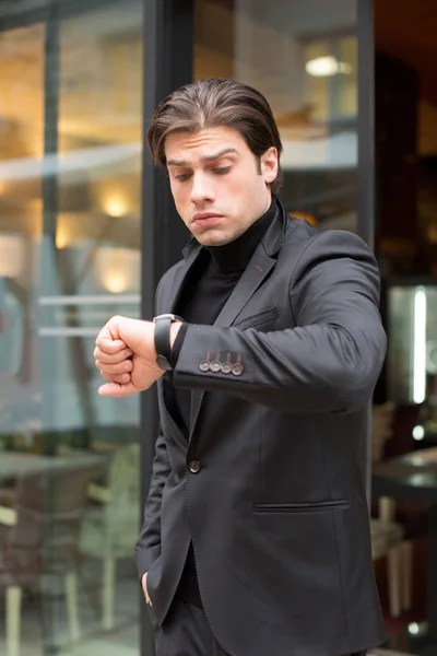 Handsome young man looking at his watch — Stock Photo, Image