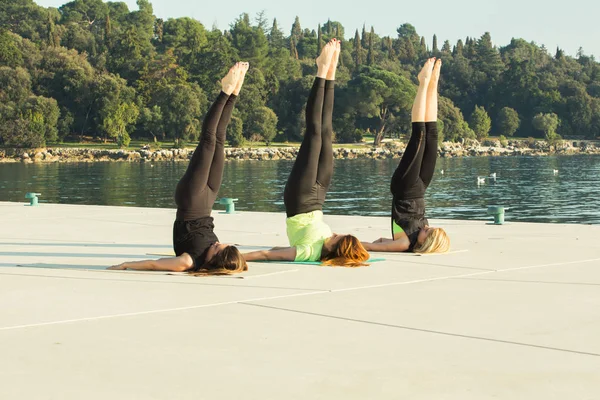 Tres mujeres jóvenes haciendo ejercicio, haciendo ejercicio de yoga — Foto de Stock