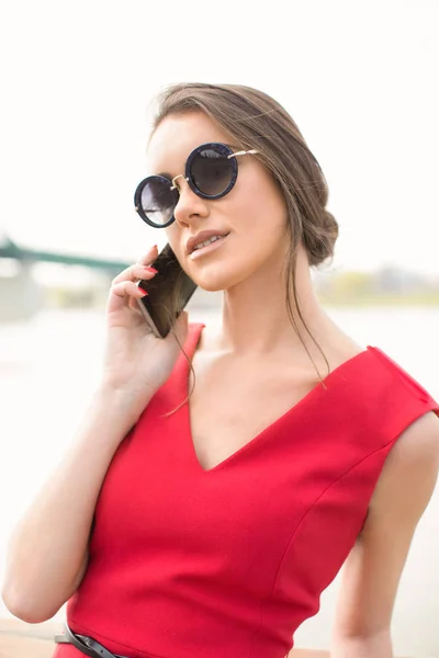Draußen, schöne Frau im roten Kleid mit Handy — Stockfoto