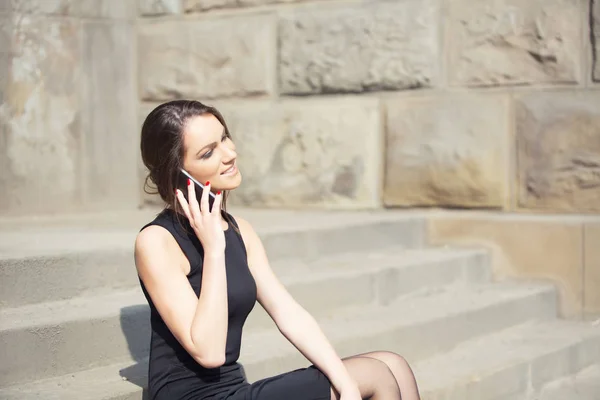 Utomhus, vacker kvinna i svart klänning med telefon — Stockfoto