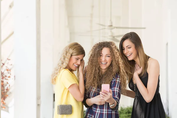 Drie jonge mooie vrouwen, meisjes, op zoek naar mobiele telefoon — Stockfoto