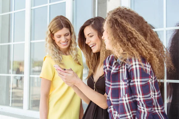 Drie jonge mooie vrouwen, meisjes, op zoek naar mobiele telefoon — Stockfoto