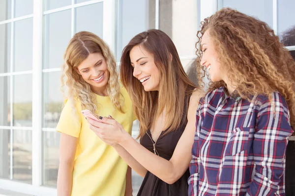 Tres mujeres hermosas jóvenes, chicas, mirando el teléfono móvil — Foto de Stock