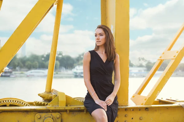 Ung, vacker kvinna som står på bron vid floden i staden — Stockfoto