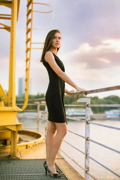 Jeune, jolie femme debout sur le pont au bord de la rivière dans la ville — Photo