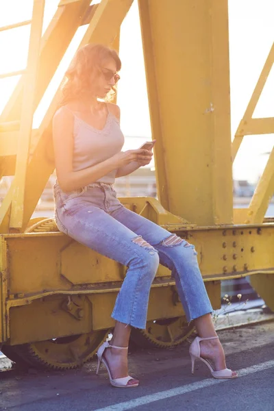 genç, güzel kadın cep telefonu ile nehir köprüsü