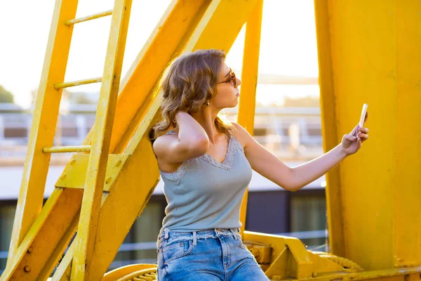 Genç, güzel kadın cep telefonu ile nehir köprüsü — Stok fotoğraf