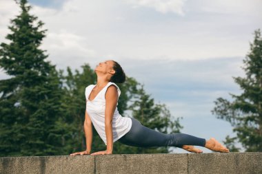 Güzel genç kadın çalışma dışarı, yoga egzersiz yaparak