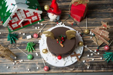 Noel ahşap masa üzerinde çikolatalı kek dekore edilmiştir.