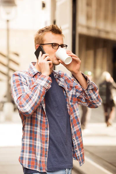 adam elinde kahve fincanı ve telefon, şehir çevre