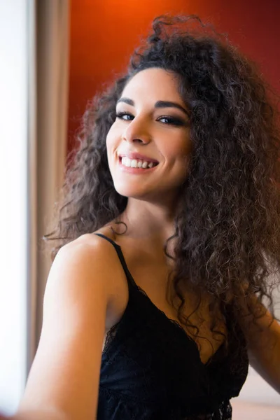 Woman with curly hair poses near window in lingerie — Stock Photo, Image