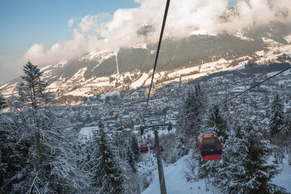 Red gondola car lift on the ski resort over forest trees
