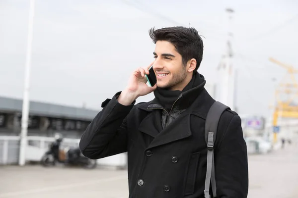 Young man with smart phone on city street in winter — Stock Photo, Image