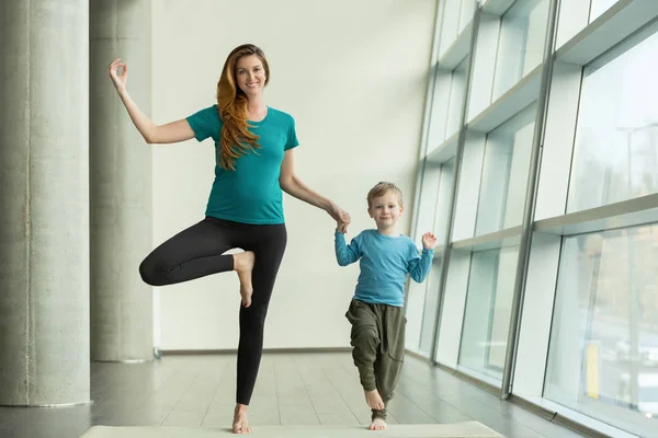 Mujer embarazada haciendo yoga prenatal con el niño — Foto de Stock