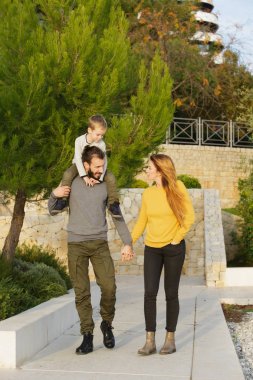 Mutlu bir aile sonbahar parkta yürüyor