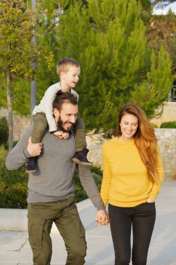 Mutlu bir aile sonbahar parkta yürüyor