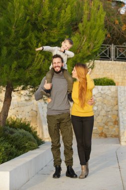 Mutlu bir aile sonbahar parkta yürüyor