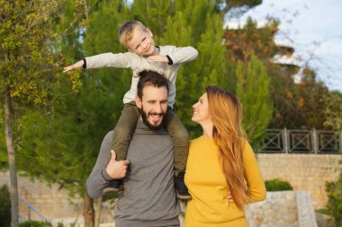 Mutlu bir aile sonbahar parkta yürüyor