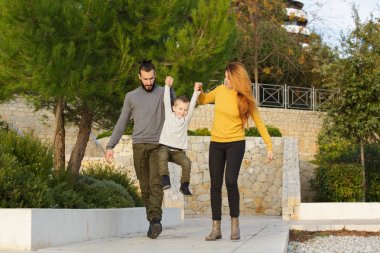 Mutlu bir aile sonbahar parkta yürüyor