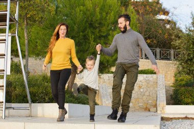 Mutlu bir aile sonbahar parkta yürüyor