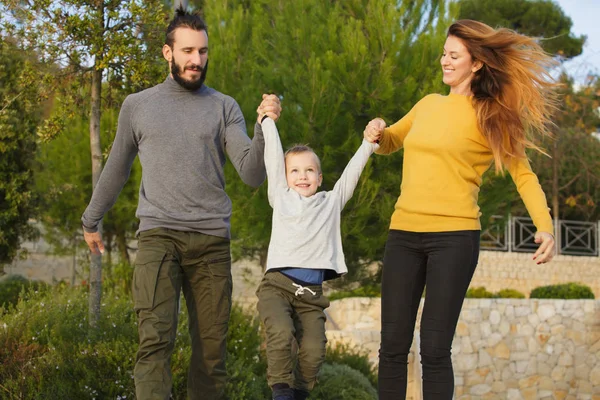 Mutlu bir aile sonbahar parkta yürüyor