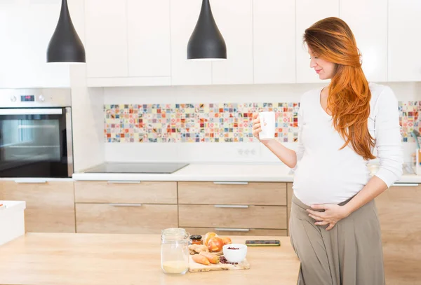 Mujer embarazada que prepara comida, verduras y bebe leche — Foto de Stock