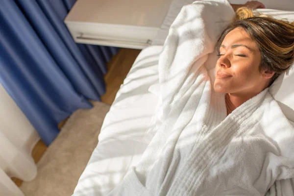 Mooie vrouw in badjas ontspannen in hotel bed — Stockfoto
