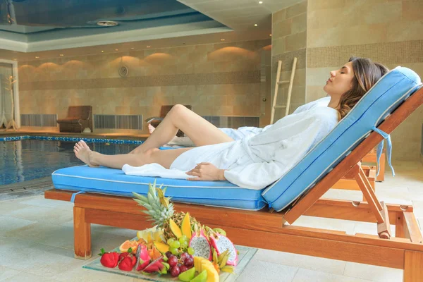 Jonge vrouw liggend op zonnebank in hotel spa centrum in de buurt van de indoor — Stockfoto